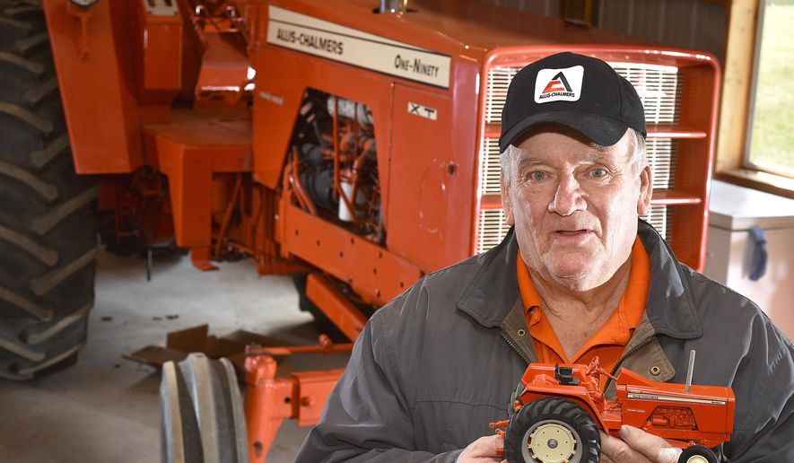Lowell Johnson holds a model of a Allis-Chamlers One-Ninety tractor in from of its full-size counterpart Monday, March 21, 2016, at his home in Belden, Neb. Johnson has a large collection of Allis-Chalmers and Case-IH farm toys. (Tim Hynds/Sioux City Journal via AP) MANDATORY CREDIT