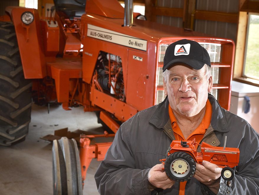 Lowell Johnson holds a model of a Allis-Chamlers One-Ninety tractor in from of its full-size counterpart Monday, March 21, 2016, at his home in Belden, Neb. Johnson has a large collection of Allis-Chalmers and Case-IH farm toys. (Tim Hynds/Sioux City Journal via AP) MANDATORY CREDIT