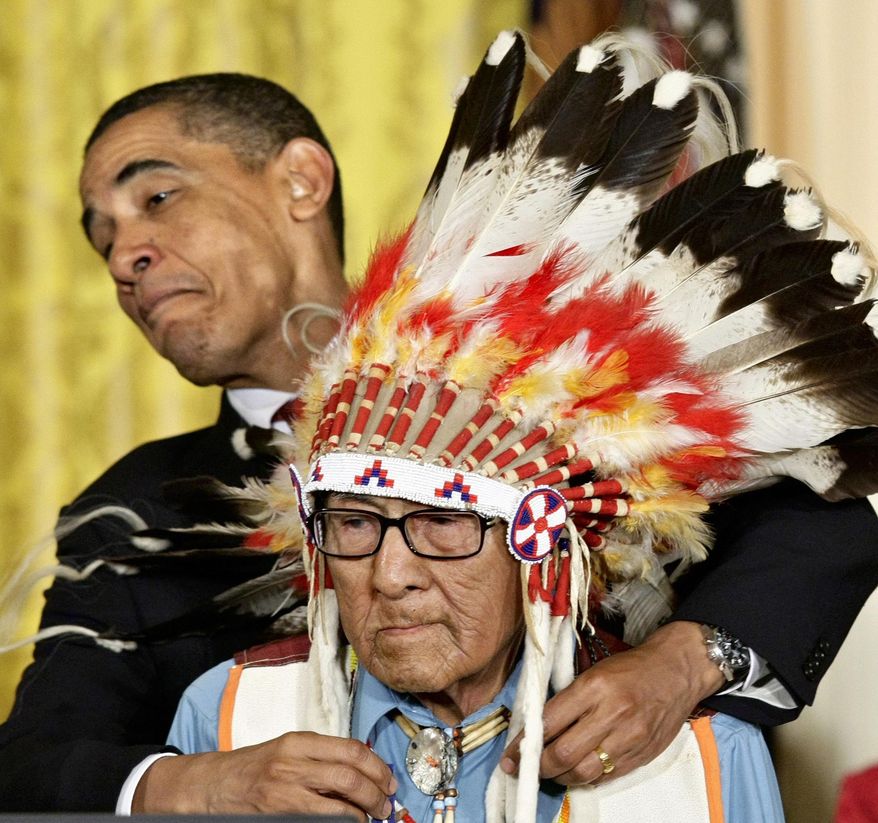 FILE - In this Aug. 12, 2009 file photo, President Barack Obama leans away to avoid the headdress as he presents the 2009 Presidential Medal of Freedom to Joseph Medicine Crow during ceremonies at the White House in Washington. Medicine Crow, the last surviving war chief for Montana's Crow Tribe, died Sunday, April 3, 2016 in a Billings hospice at age 102. Medicine Crow earned the title of war chief and a Bronze Star after stealing enemy horses and other exploits as a U.S. soldier in World War II.(AP Photo/J. Scott Applewhite, File)