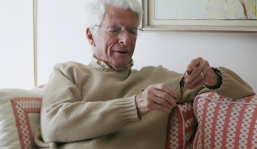 This February 2016 photo provided by Dan Shifrin shows his father, 93-year-old Edwin Shifrin at home in Clayton, Mo., looking at a prisoner-of-war medal he just received for his World War II military service. The award was expedited by U.S. Sen. Claire McCaskill of Missouri after she was approached by Shifrin's family about his clever escape from a Nazi prison camp. That may never have come to light if not for the efforts of son Dan Shifrin, who says he was able to learn about the escape by digging through old news reports and his father's military records. (Marianne Shifrin/Dan Shifrin via AP)