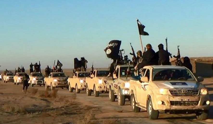 In this undated file photo released online in the summer of 2014 on a militant social media account, which has been verified and is consistent with other AP reporting, militants of the Islamic State group hold up their weapons and wave its flags on their vehicles in a convoy on a road leading to Iraq, in Raqqa, Syria. (Militant photo via AP, File)