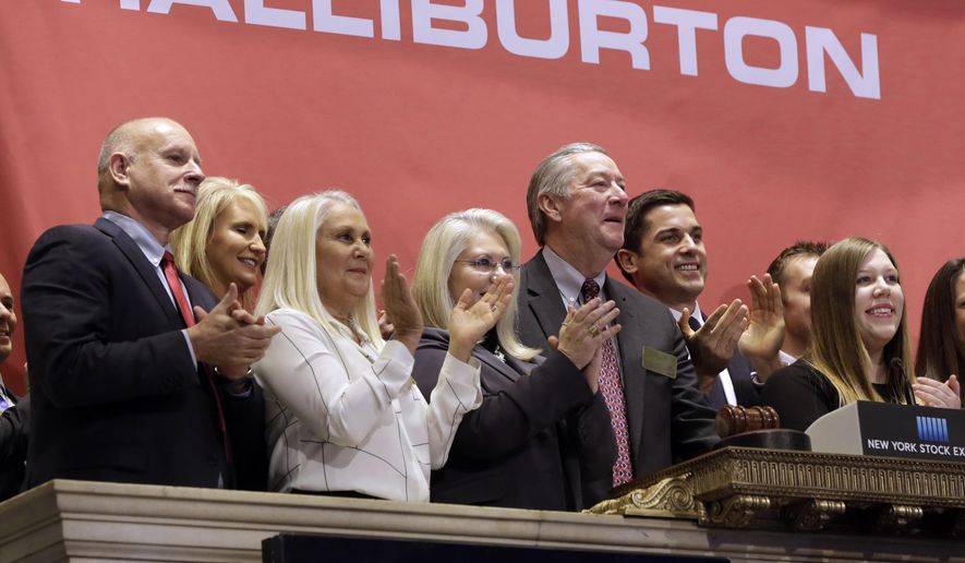 FILE - In a Nov. 18, 2014 file photo, Halliburton Chairman, President and CEO David Lesar, third from right, rings the New York Stock Exchange opening bell. Halliburton and Baker Hughes announced their plan to combine in November 2014, shortly after oil prices began to fall. The U.S. Justice Department is expected to sue to stop Halliburton Co. from acquiring rival Baker Hughes Inc., according to a person familiar with the matter. The person spoke on condition of anonymity Tuesday, April 5, 2016, because the lawsuit had not yet been announced. (AP Photo/Richard Drew, File)
