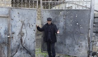 Elmar Abdullayev, 55, stands at a gates of his home hit by shelling in a village of Gapinli, in Terter region of Azerbaijan on Tuesday, April 5, 2016. Azerbaijan and separatist forces in Nagorno-Karabakhk on Tuesday agreed on a cease-fire starting noon local time following three days of the heaviest fighting in the disputed region since 1994, the Azeri defense ministry announced. Gapanli, a village south of Terter, has been one of the hardest hit. Houses bear the marks of the recent shelling; metal doors are riddled with shrapnel, power lines are cut down, craters are seen in the yards. (AP Photo/ Hicran Babayev)