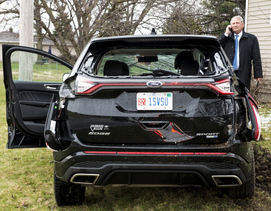 Don Bachand, Saginaw Valley State University president of Saginaw Valley State University, uses his cellphone after he was involved in a crash with a pickup truck Wednesday, April 6, 2016, in Carrolton Township, Mich. U.S. Rep. John Moolenaar, R- Midland, was a passenger in the Ford Edge driven by Bachand. (Jacob Hamilton/The Saginaw News via AP)