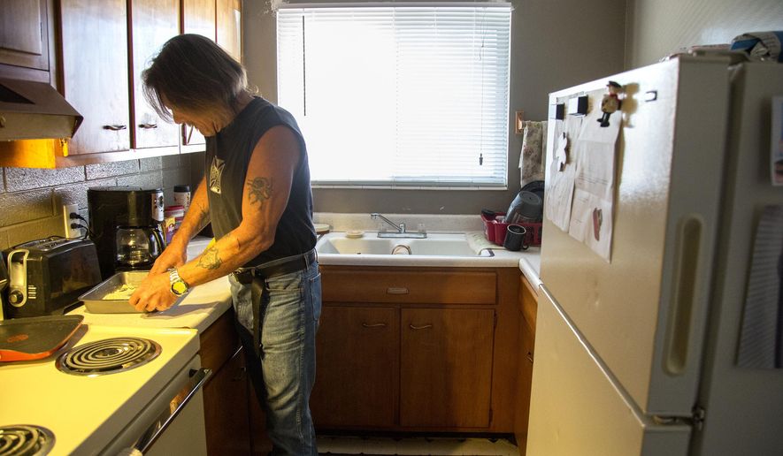 ADVANCE FOR WEEKEND EDITIONS - In this Wednesday, March 23, 2016 photo, Doug Harding prepares chicken in his kitchen in Ogden, Utah. Harding was waiting for a trip to the Joyce Hansen Hall Food Bank to restock his kitchen. (Benjamin Zack/Standard-Examiner via AP) MANDATORY CREDIT