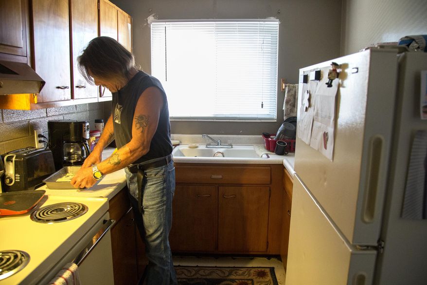 ADVANCE FOR WEEKEND EDITIONS - In this Wednesday, March 23, 2016 photo, Doug Harding prepares chicken in his kitchen in Ogden, Utah. Harding was waiting for a trip to the Joyce Hansen Hall Food Bank to restock his kitchen. (Benjamin Zack/Standard-Examiner via AP) MANDATORY CREDIT