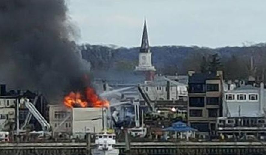 In this photo provided by Jeff Smith, fire rages from the roof of a building on the waterfront in Keyport, N.J., Friday, April 8, 2016. It wasn't immediately clear if anyone was injured in the blaze. (Jeff Smith via AP )