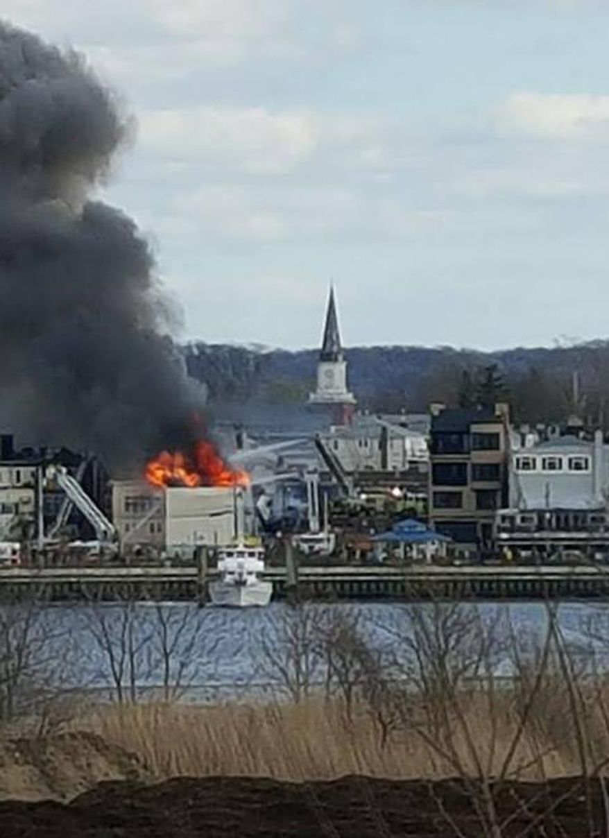 In this photo provided by Jeff Smith, fire rages from the roof of a building on the waterfront in Keyport, N.J., Friday, April 8, 2016. It wasn't immediately clear if anyone was injured in the blaze. (Jeff Smith via AP )