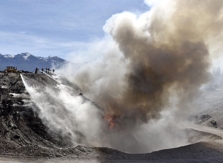 Firefighters pour water on a fire at a tire recycling facility near Pablo, Montana on Friday, April 8, 2016. The fire in a tire pit at the Tire Depot started in the morning, and agencies fighting the blaze hoped to have it contained by evening. (Tom Bauer/The Missoulian via AP)