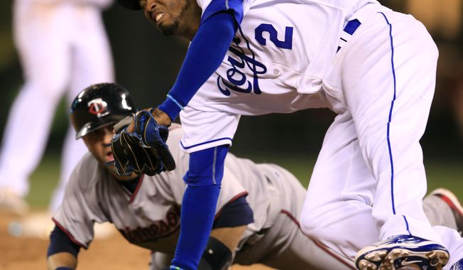 Kansas City Royals shortstop Alcides Escobar (2) falls over Minnesota Twins&#x27; Brian Dozier during a rundown between second and third bases in the ninth inning of a baseball game at Kauffman Stadium in Kansas City, Mo., Friday, April 8, 2016. Dozier was out on the play. The Royals defeated the Twins 4-3. (AP Photo/Orlin Wagner)
