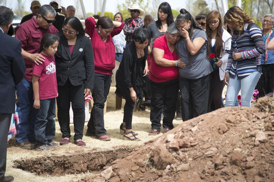 Loreal Tsingine's 8-year-old daughter, Tiffany, hugs her grandfather Edward Barnell at Tsingine's funeral on Tuesday, April 5, 2016, at Desert View Cemetery, in Winslow, Ariz. Tsingine was fatally shot by a Winslow police officer. (Mark Henle/The Arizona Republic via AP)
