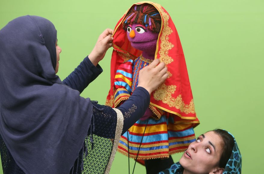 In this Wednesday, April 6, 2016, photo, an Afghan puppeteer left, adjusts a scarf on Sesame Street's new character, a sassy, fun 6-year-old Afghan puppet girl called Zari during a recording session ahead of her television debut on Afghanistan's local production of the show in Kabul. Zari - whose name means “shimmering” in Afghanistan’s two official languages, Dari and Pashtu - made her debut on Thursday on the fifth season of Afghanistan’s local production of the show called Baghch-e-Simsim, which translates as Sesame Garden. (AP Photo/Rahmat Gul)
