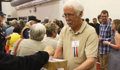 Dennis Smyth accepts paper ballots from voters at the Laramie County Democratic Caucus held Saturday, April 9, 2016, in Cheyenne, Wyo. (Shawn Havel/The Wyoming Tribune Eagle via AP)
