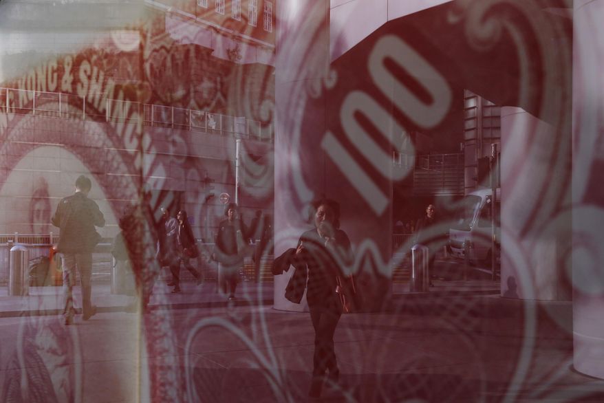 In this March 2, 2016 photo, people are reflected in a glass displaying a poster featuring a 100 dollars Hong Kong colonial bank note in Hong Kong. Hong Kong has emerged as a major design center for offshore vehicles, a place brimming with people expert at packaging and protecting wealth. The back pages of newspapers here teem with advertisements for corporate formation companies, one-stop shops promising fast bank account opening, corporate compliance, tax and accountancy services. Offshore vehicles are used to minimize tax, mitigate political risk, and circumvent onerous regulations in China. And they are completely legal. (AP Photo/Kin Cheung)