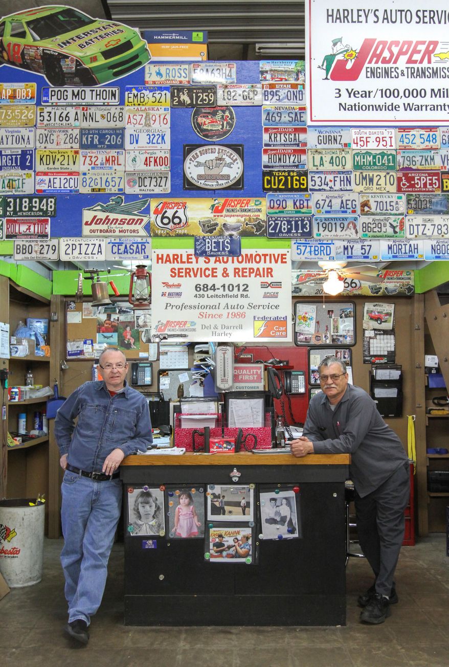 In this photo taken March 29, 2016, Del Harley left, and Darrell Harley stand in the service area of Harley’s Automotive Service & Repair in Owensboro, Ky., with a decorated wall of license plates they have collected from customers over the years. The business opened on Jan. 2, 1986. (Greg Eans/The Messenger-Inquirer via AP) MANDATORY CREDIT