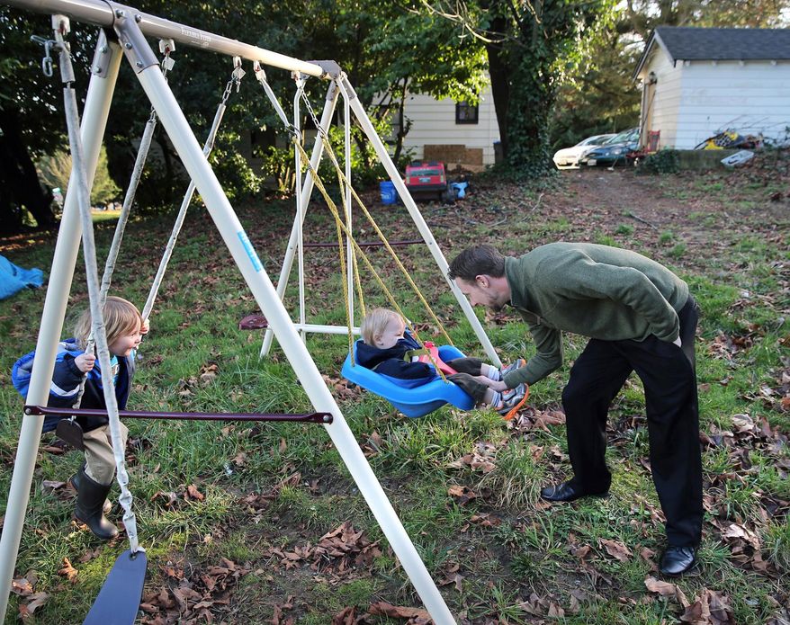 In this undated photo, Matthew Daigneault pushes his son Aden as he plays outside on the swings of his rental home in West Bremerton, Wash. Once-cheap houses and apartment buildings are being renovated and rented at higher rates. Some federally subsidized developments have been converted to market-rate rentals, eating away at the county's stockpile of affordable units. (Larry Steagall/Kitsap Sun via AP) MANDATORY CREDIT