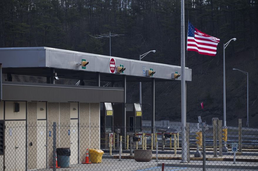 FILE - In a Monday, March 21, 2016 file photo, the Fort Littleton Pennsylvania turnpike exit flies a U.S. flag at half mast after a shooting, in Littleton, Pa. Martha Berkstresser, a Pennsylvania Turnpike toll collector who survived the botched robbery attempt that left three people dead said she was terrified but her instincts took over during the attack by a retired state trooper, who was killed by police responding to her call for help. (Mark Pynes/PennLive.com via AP, File) MANDATORY CREDIT; MAGS OUT