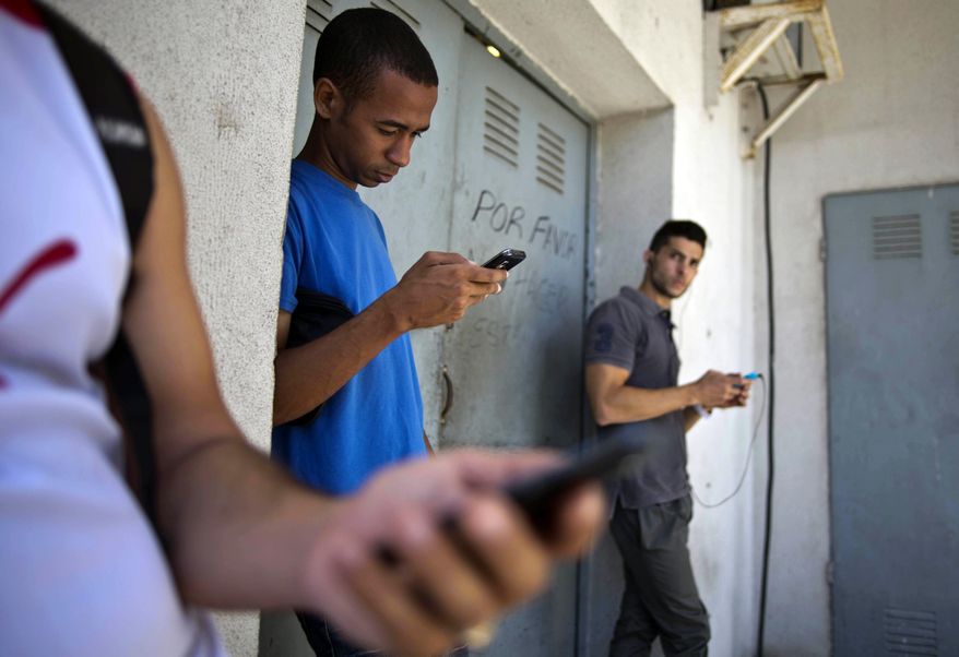 FILE - In this April 1, 2014, file photo, students gather behind a business looking for a Internet signal for their smart phones in Havana, Cuba. As U.S. officials dealt with the fallout of a once-secret "Cuban Twitter" program, they had one thing on their side: notorious delays in the federal Freedom of Information Act. (AP Photo/Ramon Espinosa, File)