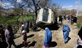 In this Monday, April 11, 2016, file, photo, Afghan women walk past a damaged bus after a roadside bomb explosion on the outskirts of Kabul, Afghanistan, The Afghan Taliban have announced the start of their warm-weather fighting season, an annual declaration that marks the launch of a summer of violence. (AP Photo/Rahmat Gul)