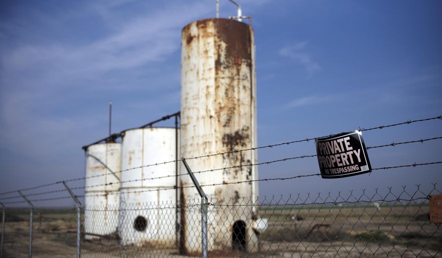 FILE - In this Jan. 15, 2015 file photo, a private property sign hangs on the fence of a shut-down injection well next to an almond orchard owned by Palla Farms in Bakersfield, Calif. Palla Farms had filed suite blaming several oil companies for contaminating the local groundwater and killing cherry trees. A federal review says the U.S. Environmental Protection Agency is failing to protect drinking water reserves from oilfield contamination. The U.S. Government Accountability Office review follows disclosures that California allowed oil companies to dump wastewater into some federally protected supplies of drinking-water. (AP Photo/Jae C. Hong, File)