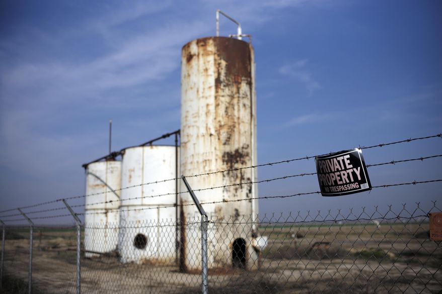 FILE - In this Jan. 15, 2015 file photo, a private property sign hangs on the fence of a shut-down injection well next to an almond orchard owned by Palla Farms in Bakersfield, Calif. Palla Farms had filed suite blaming several oil companies for contaminating the local groundwater and killing cherry trees. A federal review says the U.S. Environmental Protection Agency is failing to protect drinking water reserves from oilfield contamination. The U.S. Government Accountability Office review follows disclosures that California allowed oil companies to dump wastewater into some federally protected supplies of drinking-water. (AP Photo/Jae C. Hong, File)