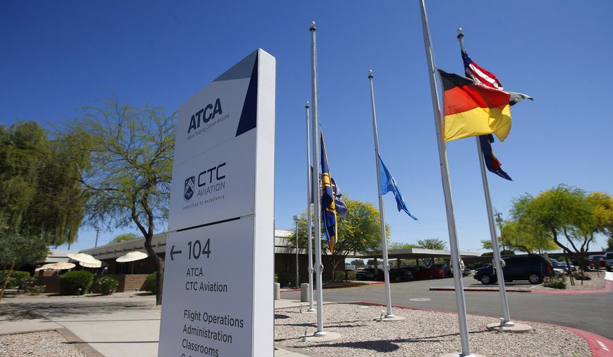 FILE - In this Mrch 26, 2015 file photo, flags, including the German flag, fly at half staff at The Airline Training Center Arizona, at the Goodyear Airport in Goodyear, Ariz. The families of victims killed last year when a suicidal pilot flew an airliner into a mountainside in the French Alps filed a lawsuit Wednesday, April 13, 2016, against the U.S. flight school where the pilot was trained, alleging the school failed to properly screen his medical background. The suit was filed in U.S. District Court in Phoenix against the Airline Training Center of Arizona. It's owned by Lufthansa, which is also the parent company of Germanwings, a regional Europe carrier that employed pilot Andreas Lubitz. (AP Photo/Ross D. Franklin, File)