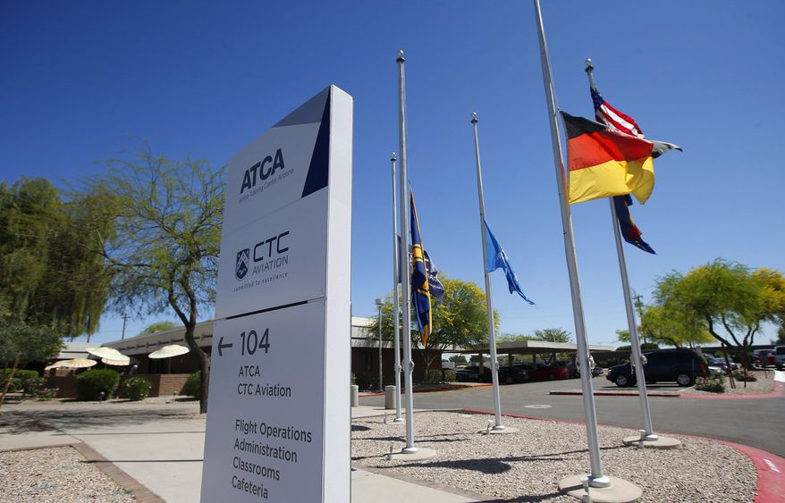 FILE - In this Mrch 26, 2015 file photo, flags, including the German flag, fly at half staff at The Airline Training Center Arizona, at the Goodyear Airport in Goodyear, Ariz. The families of victims killed last year when a suicidal pilot flew an airliner into a mountainside in the French Alps filed a lawsuit Wednesday, April 13, 2016, against the U.S. flight school where the pilot was trained, alleging the school failed to properly screen his medical background. The suit was filed in U.S. District Court in Phoenix against the Airline Training Center of Arizona. It's owned by Lufthansa, which is also the parent company of Germanwings, a regional Europe carrier that employed pilot Andreas Lubitz. (AP Photo/Ross D. Franklin, File)