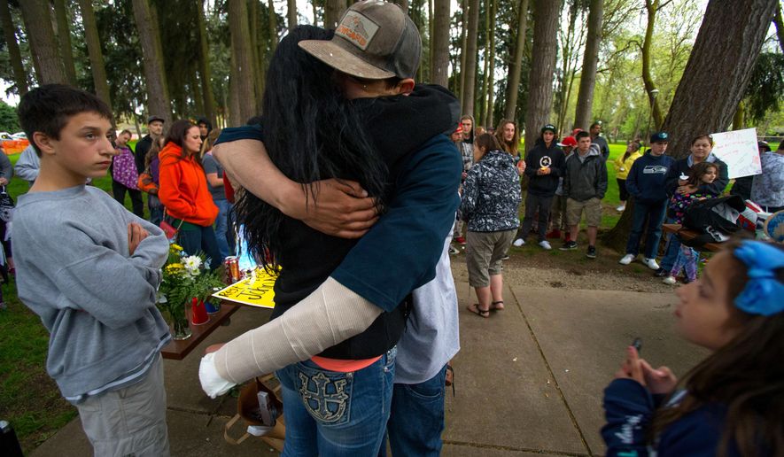 Cain Lee Barnett, 21, who suffered gunshot wounds in a murder-suicide, is embraced during a memorial service for John Mills at Emerald Park in Eugene, Ore., Wednesday, April 13, 2016. Mills, 31, was shot and killed at the park Tuesday. The shooter, Orlando Centeno, also shot and wounded Barnett, then fatally shot himself. (Brian Davies/The Register-Guard) MANDATORY CREDIT