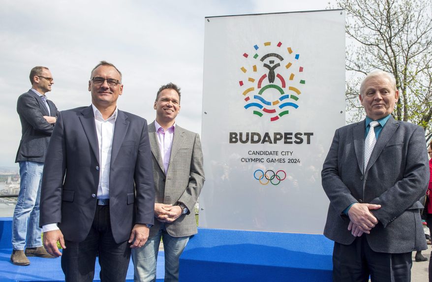 President of the Hungarian Olympic Committee Zsolt Borkai, left, Chairman of the Budapest 2024 bid Balazs Furjes, second left, and Budapest Mayor Istvan Tarlos, right, pose in front of the logo of host city candidate Budapest for the 2024 Olympic and Paralympic Games during its presentation ceremony held on the Gellert Hill in Budapest, Hungary, Thursday, April 14, 2016. The key elements of the logo are the Statue of Liberty, center, the water and the five Olympic rings. (Tibor Illyes/MTI via AP)