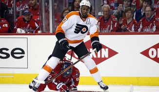 Philadelphia Flyers right wing Wayne Simmonds (17) skates over Washington Capitals center Evgeny Kuznetsov (92), from Russia, during the second period of Game 1 in the first round of the NHL Stanley Cup hockey playoffs, Thursday, April 14, 2016, in Washington. (AP Photo/Alex Brandon)