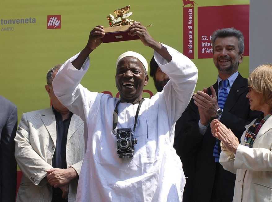 FILE - In this Sunday June 11, 2007 file photo, Mali's photographer Malick Sidibe, center, holds up the Golden Lion prize he was awarded at the 52nd Venice Biennale International Art Exhibition in Venice, Northern Italy. Malick Sidibe, whose black-and-white images captured popular culture in 1960s Bamako, died late Thursday April 14, 2016, from complications of diabetes. He was 80 years old. (AP Photo/Luigi Costantini, File)