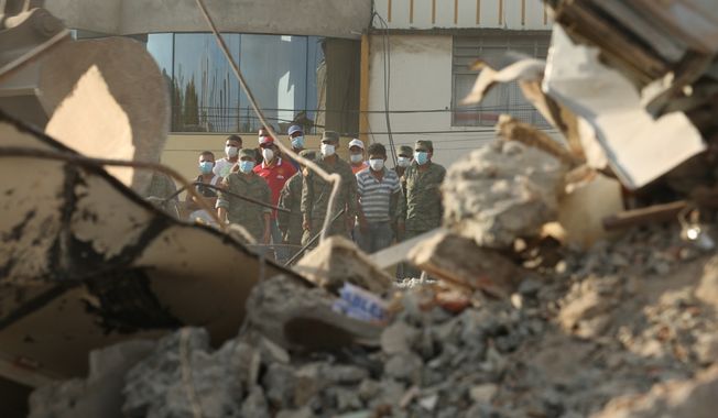 Rescue workers stand behind rubble after an earthquake in Portoviejo, Ecuador, Sunday, April 17, 2016. Rescuers pulled survivors from the rubble Sunday after the strongest earthquake to hit Ecuador in decades flattened buildings and buckled highways along its Pacific coast on Saturday night. The magnitude-7.8 quake killed hundreds of people. (AP Photo/Carlos Sacoto)