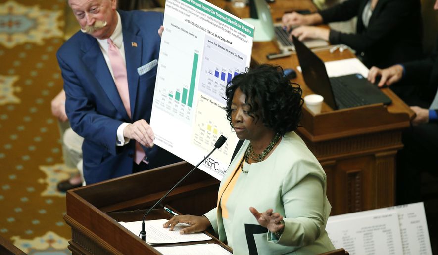 Rep. Omeria Scott, D-Laurel, right, has House Ways and Means Committee chairman Jeff Smith, R-Columbus, hold a poster she has developed that she says shows the proposed Taxpayer Pay Raise of 2016, a tax cut bill, benefits the wealthy, in House chambers, as lawmakers try to iron out the state&#39;s 2017 fiscal year budget at the Capitol in Jackson, Miss., Monday, April 18, 2016. (AP Photo/Rogelio V. Solis)