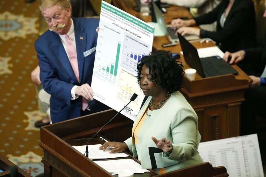 Rep. Omeria Scott, D-Laurel, right, has House Ways and Means Committee chairman Jeff Smith, R-Columbus, hold a poster she has developed that she says shows the proposed Taxpayer Pay Raise of 2016, a tax cut bill, benefits the wealthy, in House chambers, as lawmakers try to iron out the state's 2017 fiscal year budget at the Capitol in Jackson, Miss., Monday, April 18, 2016. (AP Photo/Rogelio V. Solis)
