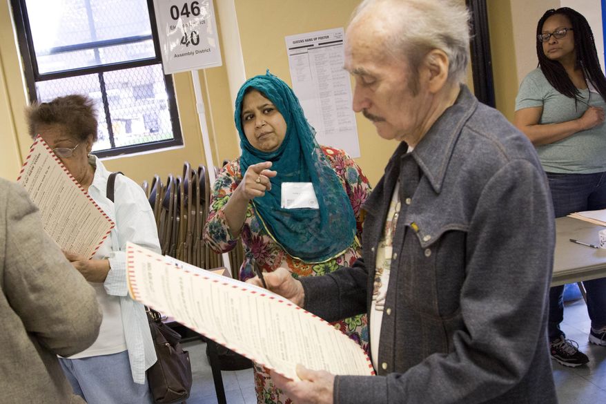 Poll worker Tahmina Banu, center, instructs an identified voter, Tuesday, April 19, 2016, in the Flushing neighborhood in the Queens borough of New York. Banu is originally from Bangladesh. (AP Photo/Mark Lennihan)