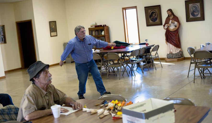 In this April 2, 2016 photo, Alan Smallwood, of Bourbonnais, Ill., throws a dart while John Lurgio, of L'Erable, Ill., left, keeps score in a game of dartball in the parish hall of St. John the Baptist Church in L'Erable. The objective is to hurl 10-inch darts at a board 25 feet away. When they stick, they count as balls, strikes, outs or any of the hits that count in a normal game of baseball. (Nicholas Holstein/The Daily Journal via AP) MANDATORY CREDIT