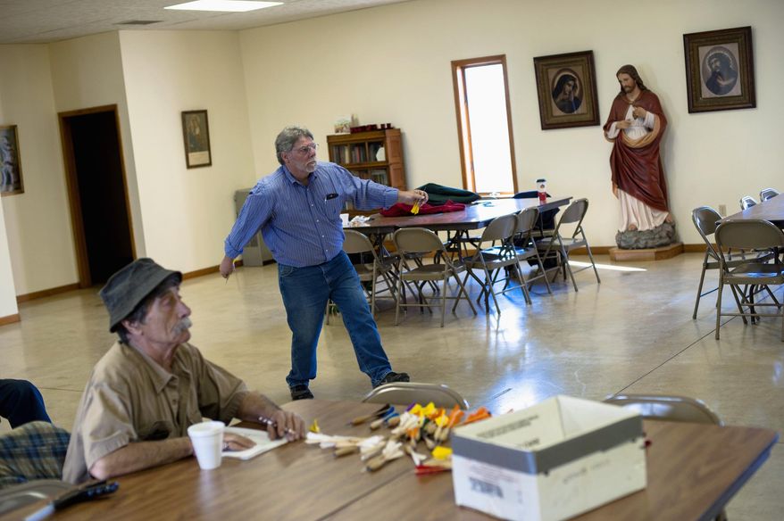 In this April 2, 2016 photo, Alan Smallwood, of Bourbonnais, Ill., throws a dart while John Lurgio, of L'Erable, Ill., left, keeps score in a game of dartball in the parish hall of St. John the Baptist Church in L'Erable. The objective is to hurl 10-inch darts at a board 25 feet away. When they stick, they count as balls, strikes, outs or any of the hits that count in a normal game of baseball. (Nicholas Holstein/The Daily Journal via AP) MANDATORY CREDIT