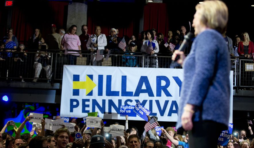 Protesters hold up signs as Democratic presidential candidate Hillary Clinton speaks at a campaign stop, Wednesday, April 20, 2016, in Philadelphia. (AP Photo/Matt Rourke)