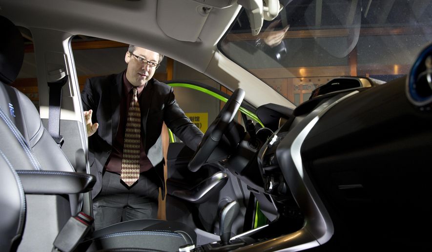 In this photo taken Monday, April 11, 2016, Michael Austin, BYD Co.'s vice president for the United States, looks at the interior of the latest plug in mini-SUV during the BYD Dreams Conference in Beijing, China. The Chinese automaker that sold more electric cars last year than Tesla, Nissan and GM combined is taking a back road into the American market on a battery-powered bus. (AP Photo/Ng Han Guan)