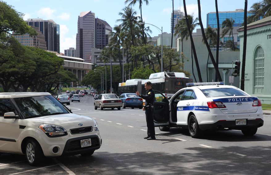 A Honolulu police officer directs traffic on a downtown street on Wednesday, April 20, 2016 in Honolulu. Hawaii lawmakers are considering a bill to clarify the public's right to photograph or film police officers as long as it doesn't interfere with law enforcements' duties. (AP Photo/Marina Riker)