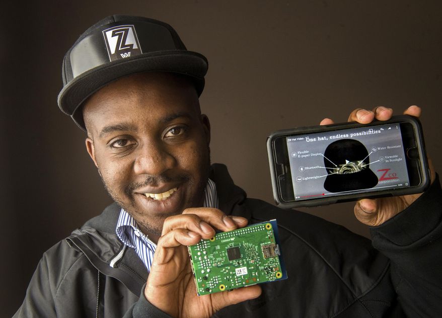 In this March 16, 2016 photo, Jamaal Crayton, of Peoria, Ill., shows a prototype of a ball cap that will feature a live display that allows the wearer to change the graphics on the hat in real-time, synced by Bluetooth to their phone. The Zero Wearables hat will eventually use a flexible paper display that can be built into the front of the hat. (Fred Zwicky/Journal Star via AP) MANDATORY CREDIT