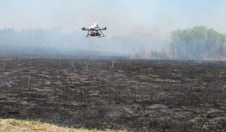 A drone designed to ignite controlled grass fires comes in for a landing in a field at the Homestead Monument of America in Beatrice, Neb., on Friday, April 22, 2016. University of Nebraska-Lincoln researchers are testing the drone as a possible tool for firefighters. (AP Photo/Grant Schulte)