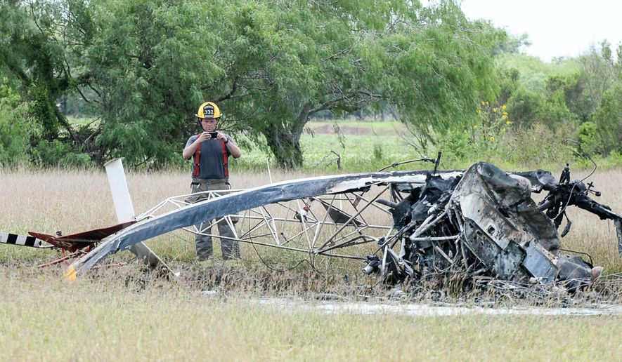 CORRECTS NAME OF VALLEY REGIONAL MEDICAL CENTER - A firefighter with the Los Fresnos, Texas Fire Department takes photographs of the scene where a helicopter crashed on Thursday, April 21, 2016, in Los Fresnos, Texas. Authorities state the helicopter made contact with nearby power lines, causing the pilot to lose control and crash in an open field. The pilot was taken to Valley Regional Medical Center in Harlingen, pending transfer to a burn ward in San Antonio. (Jason Hoekema/The Brownsville Herald via AP)