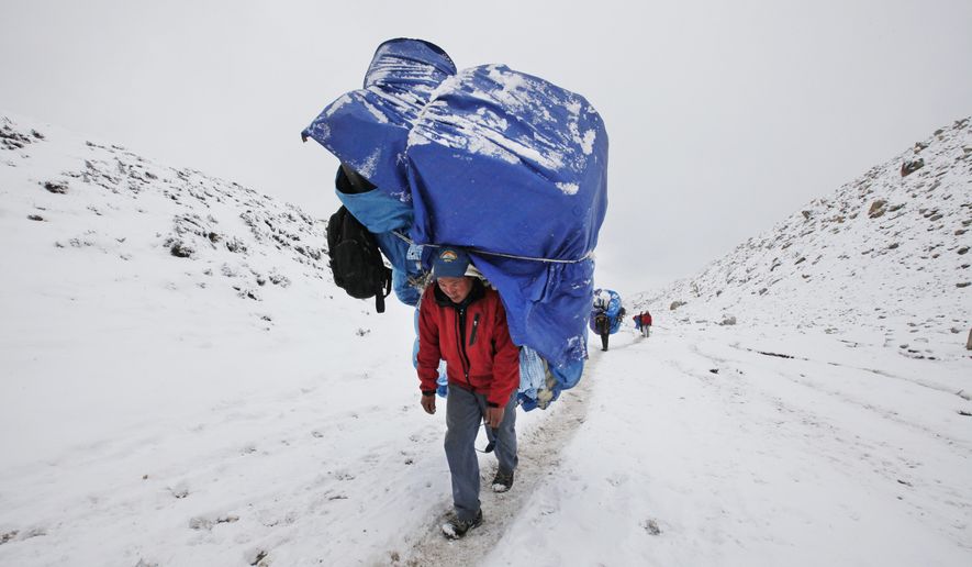 In this March 28, 2016 photo, a porter walks with a massive load towards Everest Base camp near Lobuche, Nepal. The April 2014 avalanche, which killed 13 Sherpa guides and three other Nepali workers, was an immense blow to the Sherpa community. Nearly all the surviving Sherpas refused to continue working that year, demanding, among other things, better working conditions, more insurance, and free education for the children of those killed. Over the past two years the government has enacted a series of policy changes, from stationing officials at Base Camp to creating a welfare fund for the families of the Sherpa dead, in large part to convince climbers and trekkers to keep coming back to Everest. (AP Photo/Tashi Sherpa)