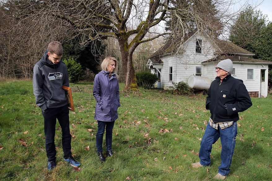 ADVANCE FOR THE WEEKEND OF APRIL 23-24 AND THEREAFTER - In a March 16, 2016 photo, members of the Rova family, from the left Erik Morgan, his mother Marsha Rova, and her brother John Rova, stand on their grandfather’s property in Poulsbo, Wash. When Eva Rova Barnes died in 2011 weeks shy of her 95th birthday, her will gave her sizable stake in the 46 acres, along with other nearby real estate and the rest of Barnes' property, to her friend and caretaker, Michelle Velarde, whom she got to know years before as her mail carrier. The family descendants regained the land in a supreme court ruling. (Larry Steagall/Kitsap Sun via AP) MANDATORY CREDIT