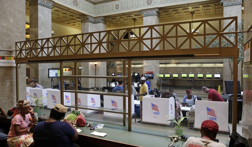 A line of voting booths are seen though glass past library patrons as people cast their votes inside the Enoch Pratt Free Library in Baltimore, Tuesday, April 26, 2016. Maryland voters have many choices and deeper impact than in recent elections as they make their choices about who should run for president and pick candidates for an open U.S. Senate seat. (AP Photo/Patrick Semansky)