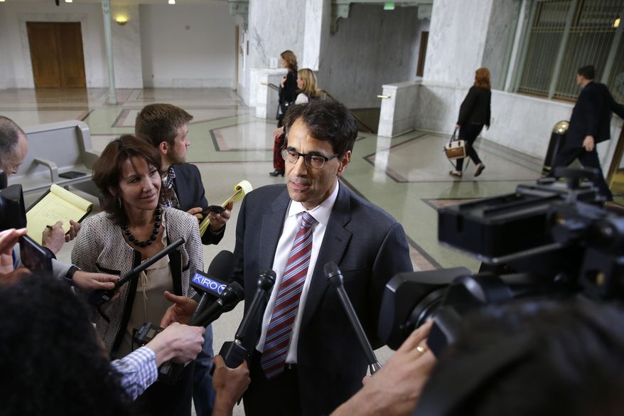 Washington State Auditor Troy Kelley can be seen in the background at far right rushing to an exit staircase as his attorney, Angelo Calfo, center, talks to reporters following the conclusion of Kelley's federal fraud trial Tuesday, April 26, 2016, in Tacoma, Wash. A jury on Tuesday failed to reach a verdict on key charges against Kelley, and acquitted him on the single count where they could agree. (AP Photo/Ted S. Warren)