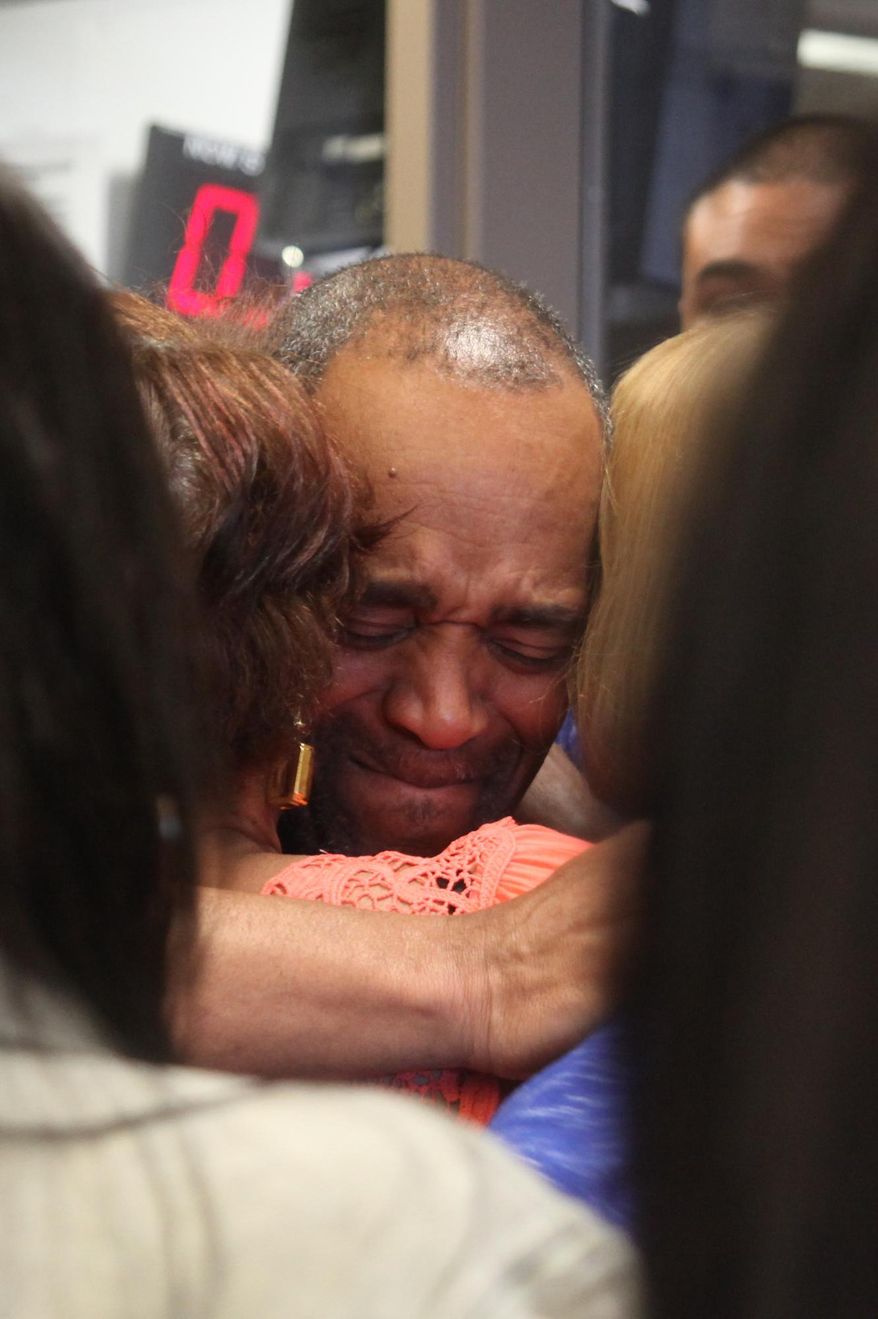 In this photo taken Monday, April 25, 2016, Darryl Pinkins is embraced by family in the lobby of the Lake County Jail in Crown Pointe, Ind., after he was released after serving more than two decades in prison for a gang rape in which he was recently cleared. (Tony V. Martin/The Times via AP) MANDATORY CREDIT; CHICAGO LOCALS OUT; GARY OUT