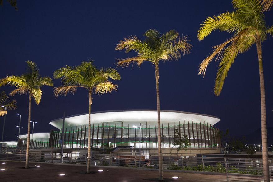 This April 11, 2016 photo shows Carioca Arena 1 behind palm trees inside Rio 2016 Olympic Park in Rio de Janeiro, Brazil. The arena will host Olympic basketball matches. Problems still hang over South America's first games. Brazil President Dilma Rousseff is being impeached and is likely to be suspended when the games open Aug. 5, partly fallout from Brazil's worst recession in decades, 10-percent unemployment, and a $3 billion Petrobras corruption scandal. Away from politics, the Zika virus threatens athletes and tourists. (AP Photo/Felipe Dana)