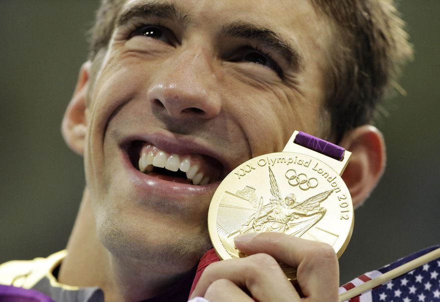 FILE - In this July 31, 2012 file photo, United States' Michael Phelps poses with his gold medal for the men's 4x200-meter freestyle relay swimming final at the Aquatics Centre in the Olympic Park during the 2012 Summer Olympics in London. If the Rio de Janeiro Olympics were held today, the United States would win the most medals and the most gold medals. And American swimmer Michael Phelps would collect five more gold medals and a bronze, bringing his overall total to 28 with a career gold-medal haul to 23. (AP Photo/Matt Slocum, File)